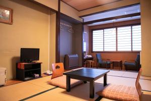 a living room with a table and a tv at Hosenji Kanko Hotel Yumotoya in Kokonoe