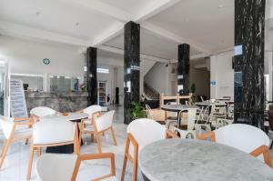 een restaurant met witte tafels en witte stoelen bij RedDoorz near UISU teladan Medan in Medan