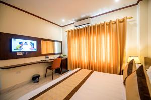 a bedroom with a bed and a desk and a tv at Premier Vang Vieng Hotel in Vang Vieng