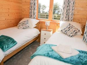 a bedroom with two beds and a window at Ty Will, Parc Y Fronwen in Newborough