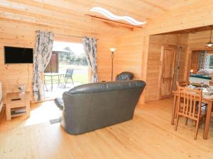 a living room with a leather couch and a table at Ty Will, Parc Y Fronwen in Newborough