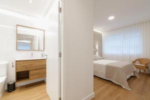 a bedroom with a bed and a sink and a mirror at LUXURY SILGAR in Sanxenxo
