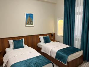 2 camas en una habitación con cortinas azules en Hotel Shakhname, en Samarkand
