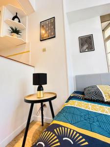 ein Schlafzimmer mit einem Bett und einem Tisch mit einer Lampe in der Unterkunft Studio chaleureux in Laon