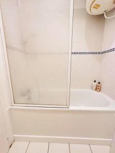 ein weißes Bad mit einer Dusche und einer Glastür in der Unterkunft Studio chaleureux in Laon