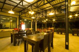 un restaurante con mesas de madera, sillas y luces en The Rise Resort, en Sukhothai