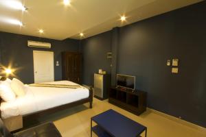 a bedroom with a bed and a tv in it at The Rise Resort in Sukhothai