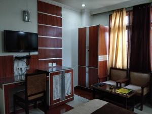 a living room with a tv and a desk and a couch at Hotel Yatrik in Jhānsi