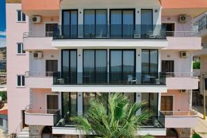 an apartment building with balconies and a palm tree at Hotel Piccolino in Sarandë