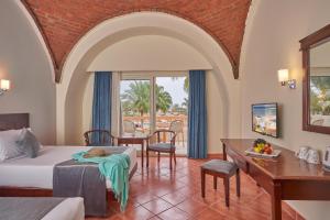 Habitación de hotel con cama, mesa y sillas en Three Corners Sea Beach Resort, en Coraya Bay