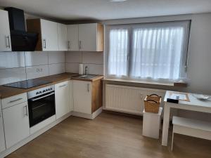 Una cocina con gabinetes blancos y un fregadero y una ventana. en Ferienwohnung Hanna, en Stockach