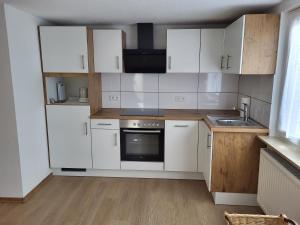Una cocina con gabinetes blancos y un fregadero. en Ferienwohnung Hanna, en Stockach