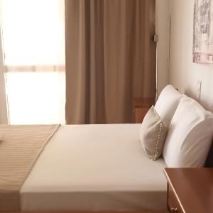 Akrogiali Apartments في باراليا سكوتنيس: سرير بشرشف ووسائد بيضاء في الغرفة