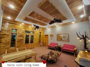 a living room with wooden ceilings and red chairs at Das-e-Basi in Gilgit