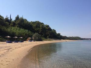 a beach with some chairs and umbrellas and the water at Elegant Maisonettes Elena in Nea Potidaea