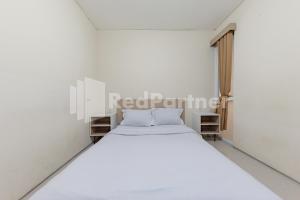 a white bedroom with a white bed and a window at Maleo Residence Bandung Mitra RedDoorz in Bandung