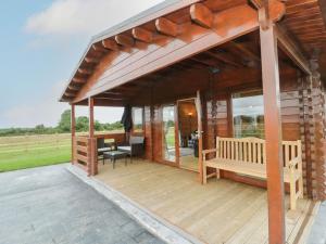 a wooden deck with a pavilion with a bench on it at Ty Presto, Parc Y Fronwen in Newborough