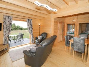 a living room with a leather couch and a table at Ty Presto, Parc Y Fronwen in Newborough