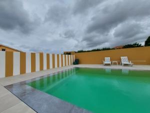 洛里尼揚的住宿－Cantinho do Sol (Estúdio Prata)，一座游泳池,旁边设有两把白色椅子