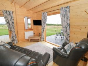 a living room with a leather couch and a television at Ty Presto, Parc Y Fronwen in Newborough