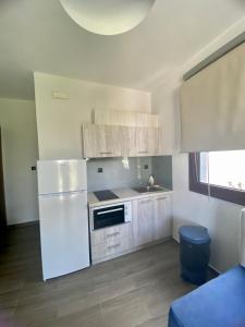 a kitchen with a white refrigerator and a sink at Hill Sun Luxury Suites in Nea Irakleia