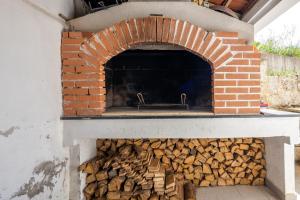 een bakstenen oven met een stapel brandhout bij Apartman Nada in Sinj