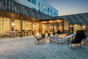 un patio avec des chaises et un foyer extérieur en face d'un bâtiment dans l'établissement Courtyard by Marriott Savannah Airport, à Savannah