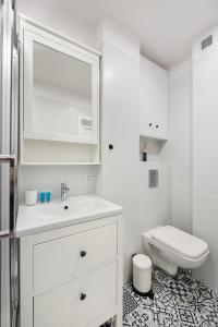 a white bathroom with a sink and a toilet at Nowogrodzka Grey Apartment in Warsaw