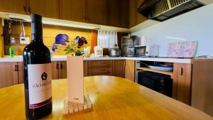 a bottle of wine sitting on a wooden table in a kitchen at ログあした 船でしか行けない離島のヴィラ in Hinase