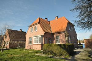 ein braunes Backsteinhaus mit orangefarbenem Dach in der Unterkunft Villa Rysum in Krummhörn