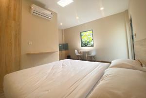 a bedroom with a large white bed and a table at ZEN garden in Xuyên Mộc