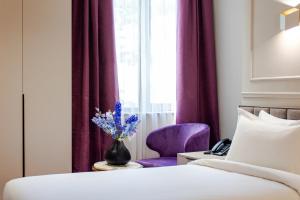 a bedroom with a bed and a vase with purple flowers at Orient Hotel Bishkek in Bishkek