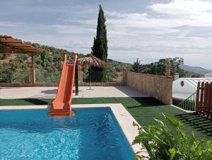 una piscina con un tobogán naranja en un patio en Casa la Pedriza Completa, en Villanueva de Algaidas