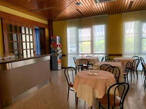 uma sala de jantar com mesas, cadeiras e janelas em Hotel Estense em Rimini