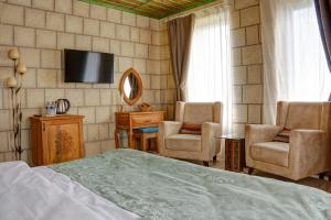 a bedroom with a bed and two chairs and a television at IVY Cappadocia in Nevsehir