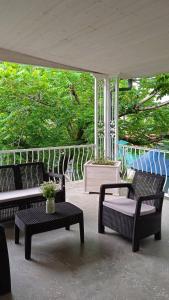 a porch with three chairs and a table and an umbrella at Qiwi House in Ureki