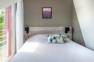 a bedroom with a white bed with a window at Zenitude Hôtel-Résidences Nantes - La Beaujoire in Nantes