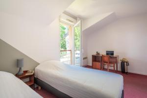 a bedroom with a bed and a desk and a window at Zenitude Hôtel-Résidences Nantes - La Beaujoire in Nantes