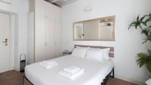 a white bedroom with a large white bed and a mirror at Italianway - Argelati 2 in Milan