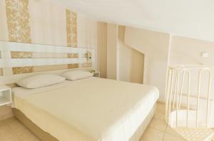 a white bedroom with a white bed with white pillows at Aegean Sun Hotel in Skala Rachoniou