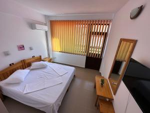 um pequeno quarto com uma cama e uma televisão em Hostel Stefania em Costinesti