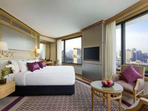 a hotel room with a bed and a large window at Grand Mercure Bangkok Atrium in Bangkok