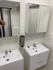 a white bathroom with two sinks and a mirror at Kinizsi Udvar Apartmanház in Balatonboglár