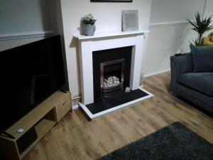 a living room with a fireplace and a tv at Blackpool Holiday Home - Forshaw House in Blackpool
