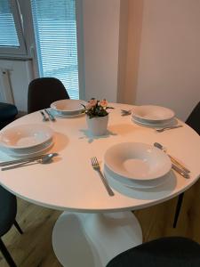 a white table with plates and utensils on it at Ada Apartment in Ljubljana +10 photos