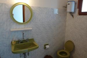 y baño con lavabo, espejo y aseo. en Chryssa Bungalows, en Ándros