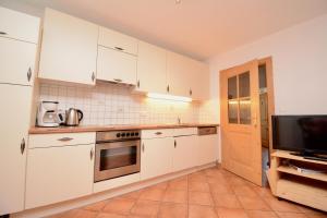a kitchen with white cabinets and a television at Appartement Oberschernthann in Hopfgarten im Brixental