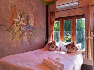 een slaapkamer met een bed met een schilderij aan de muur bij Pai Family House in Pai