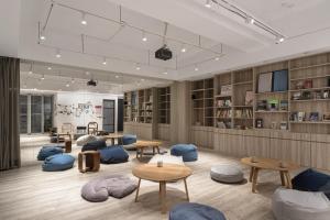 a library with tables and chairs in a room at 1LI7E Hotel in Taichung