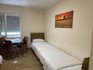 um quarto com duas camas e uma mesa e uma janela em LUX apartmani za izdavanje em Bečej